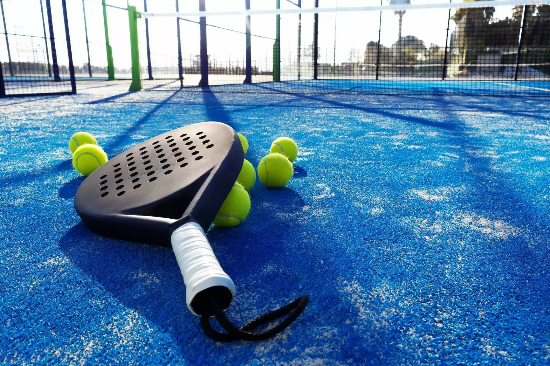 Padel racket and balls on a blue padel court